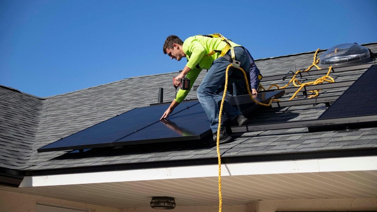 Vakman legt zonnepanelen op een dak